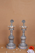 Pair of silver peacock diya stands with multi-tier stems and colorful enamel accents