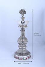 Silver peacock diya stand with central bowl, tiered stem, and round base