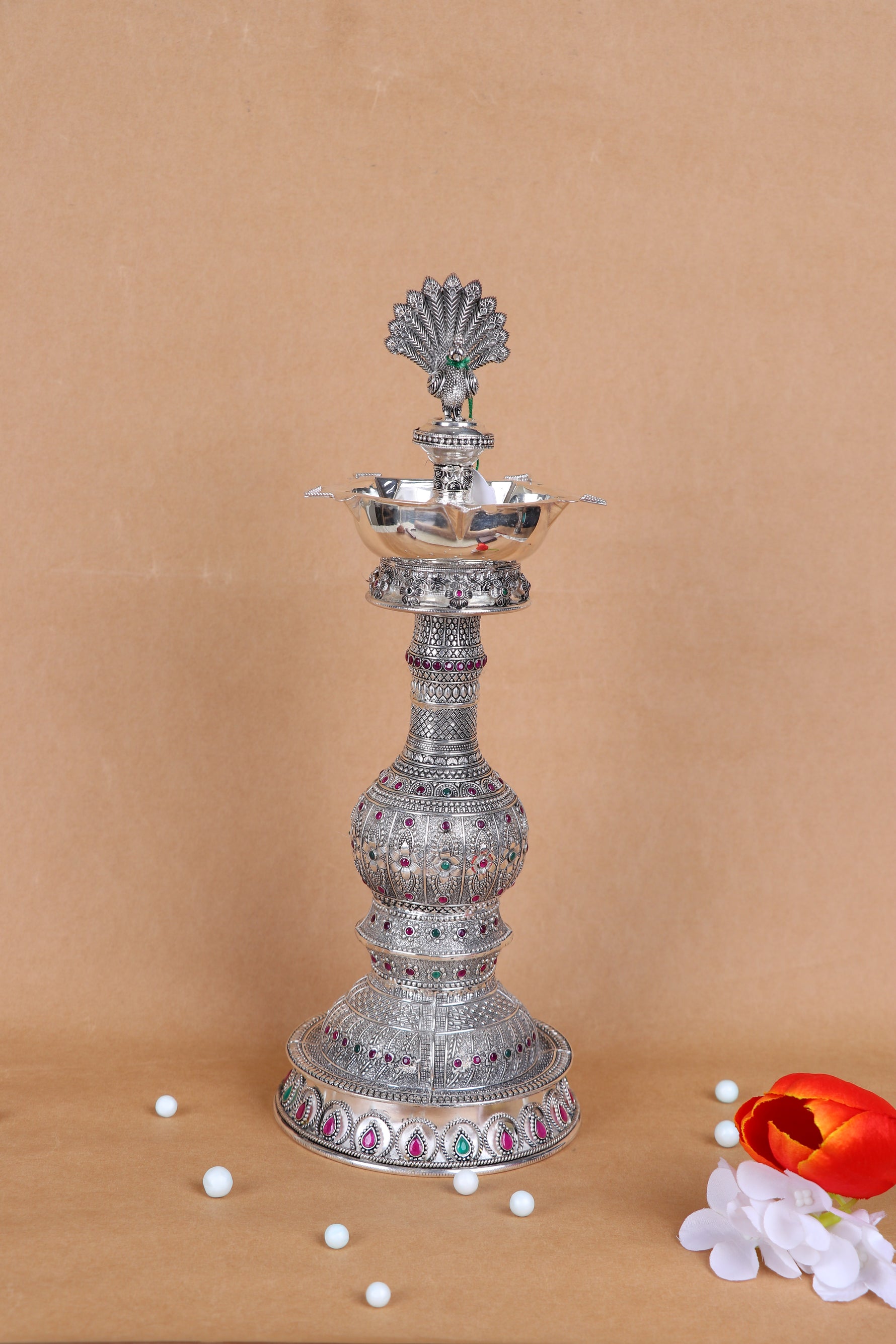 Tall silver peacock diya stand with central lamp bowl and colorful enamel details