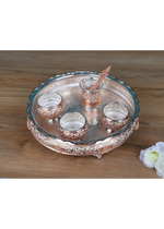 Angled view: Silver-tone pooja thali with five small cups and a center raised holder