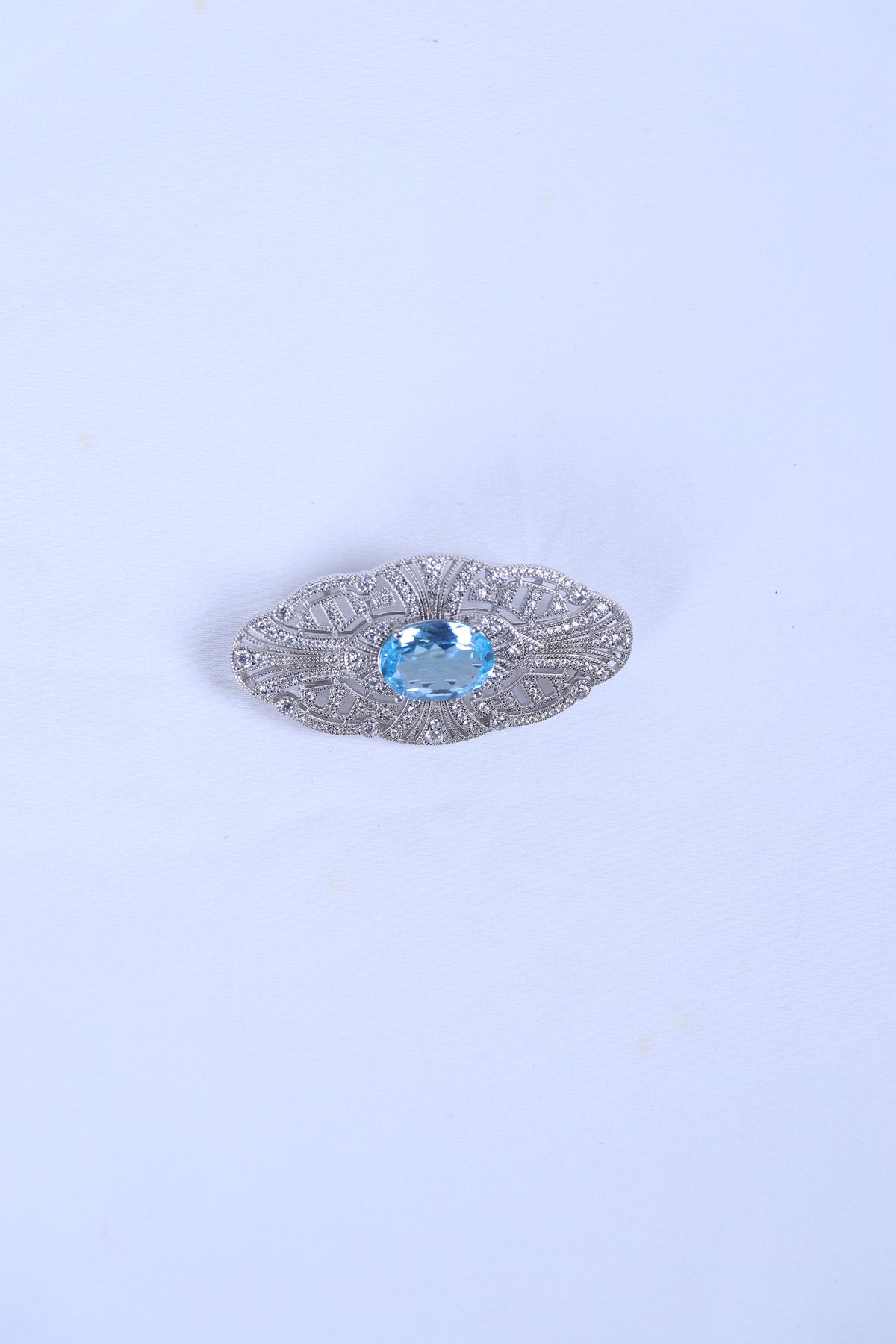 Silver filigree brooch featuring an oval blue gemstone center