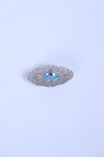 Silver filigree brooch featuring an oval blue gemstone center