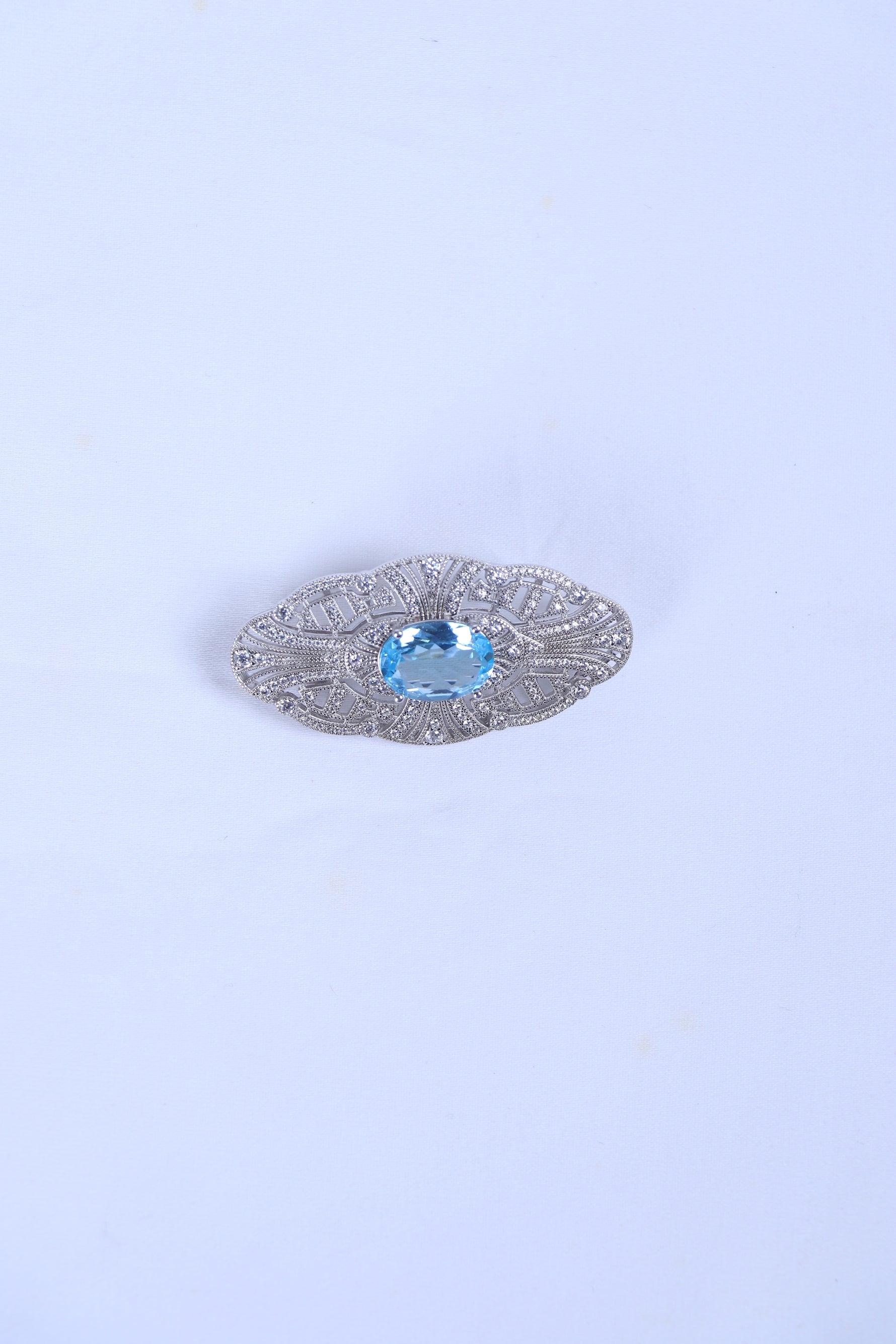 Silver filigree brooch featuring an oval blue gemstone center