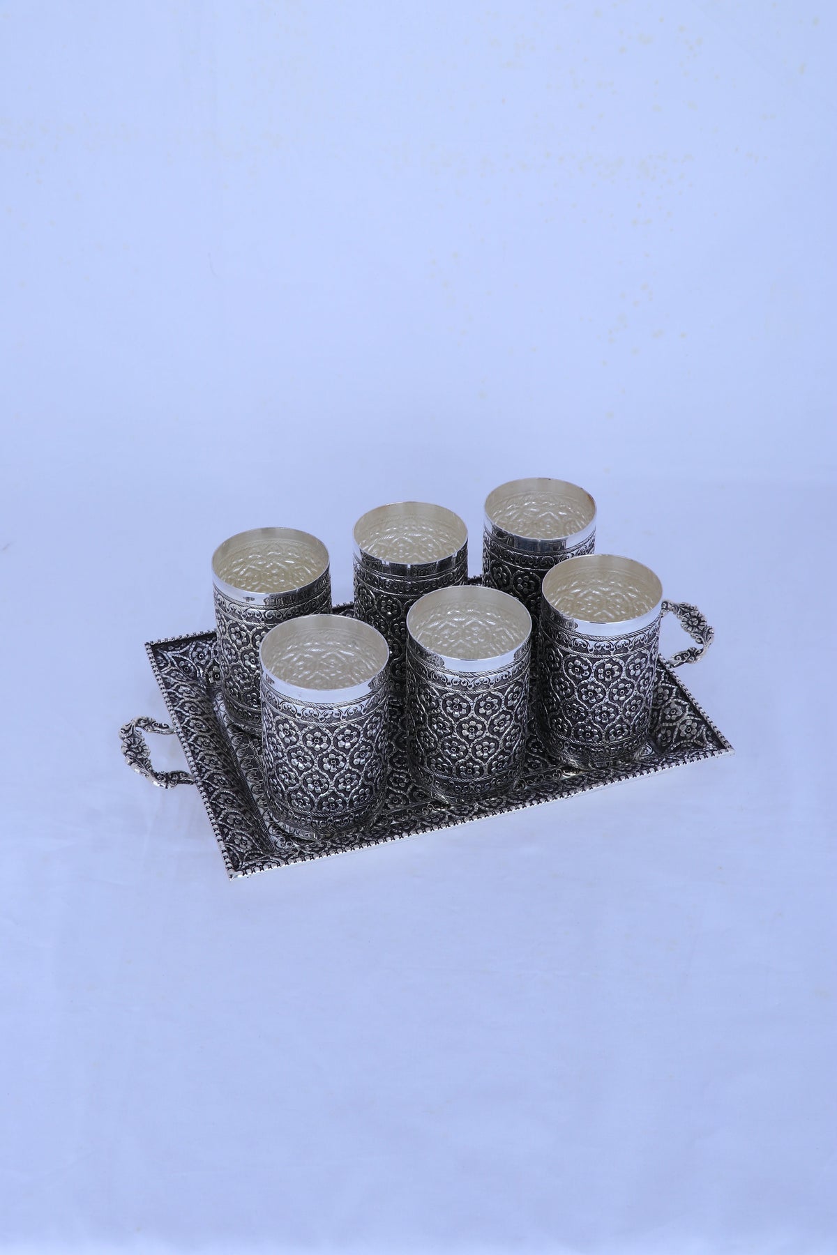 Set of silver fluted tumblers on rectangular tray with ornate geometric pattern