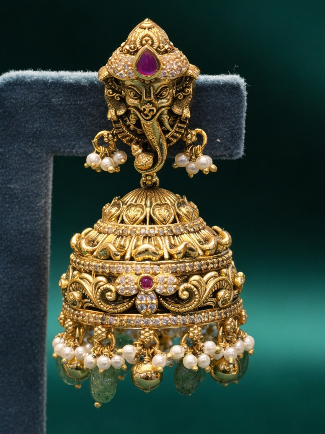 Ornate silver earring with pearls and gemstones on a dark background