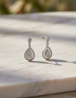 Shop crystal-studded silver dangle earrings for women with an intricate layered halo design.