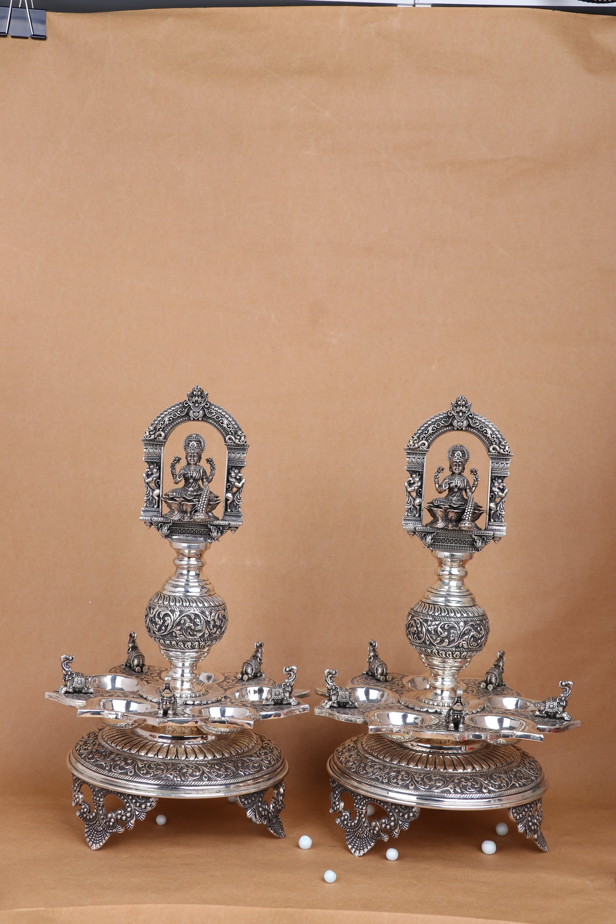 Pair of silver-tone standing temple diyas with Lakshmi relief, circular trays and claw feet