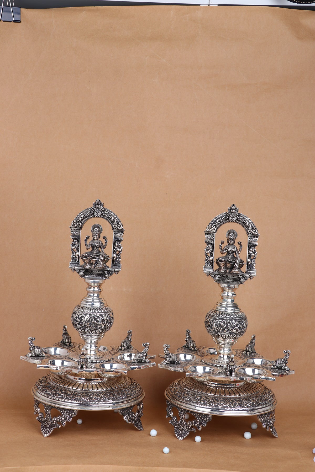 Pair of ornate silver-tone temple diyas with Lakshmi relief panels and multi-pronged trays