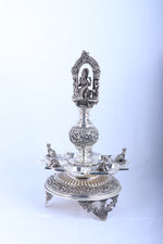Single ornate silver-tone temple diya stand with Lakshmi relief and circular base tray