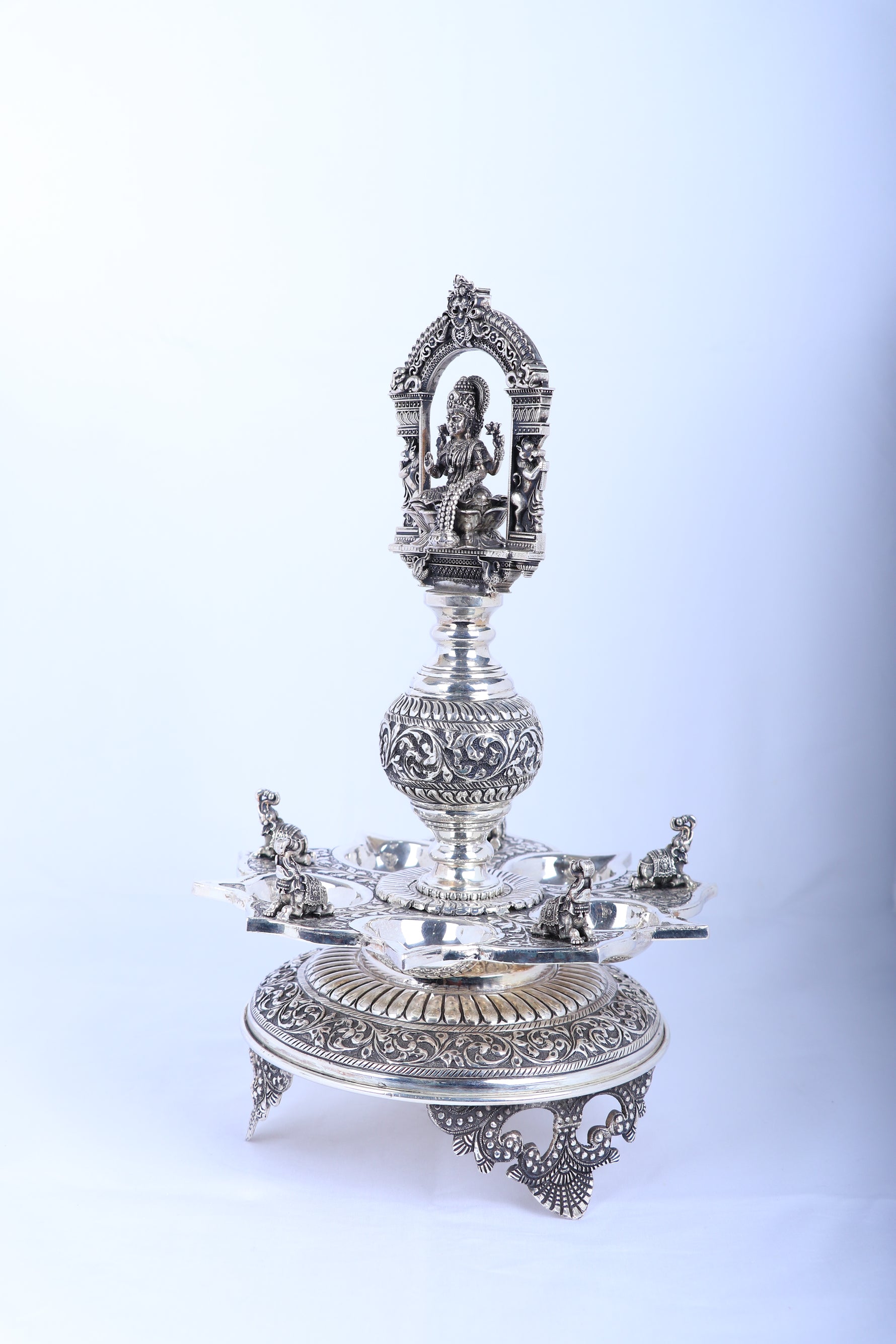 Single ornate silver-tone temple diya stand with Lakshmi relief and circular base tray