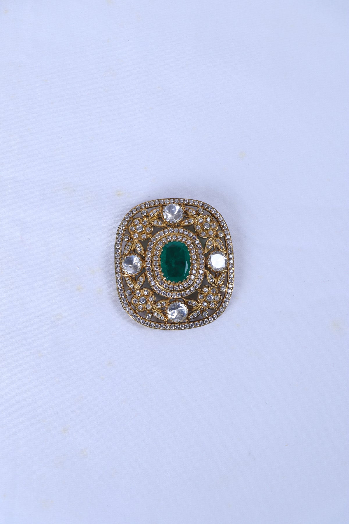 Silver brooch for men with green stone and crystal detailing on a formal sherwani.