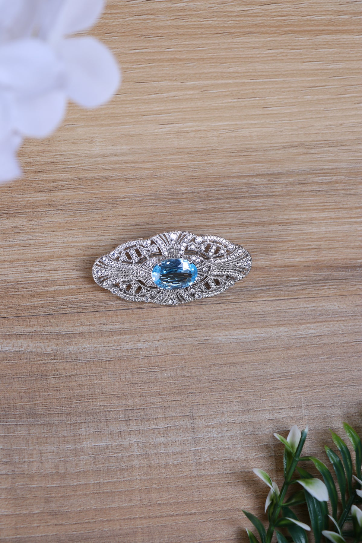 Silver filigree brooch with oval blue gemstone and decorative scrollwork