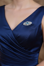 Silver filigree brooch with oval blue stone on a navy dress neckline