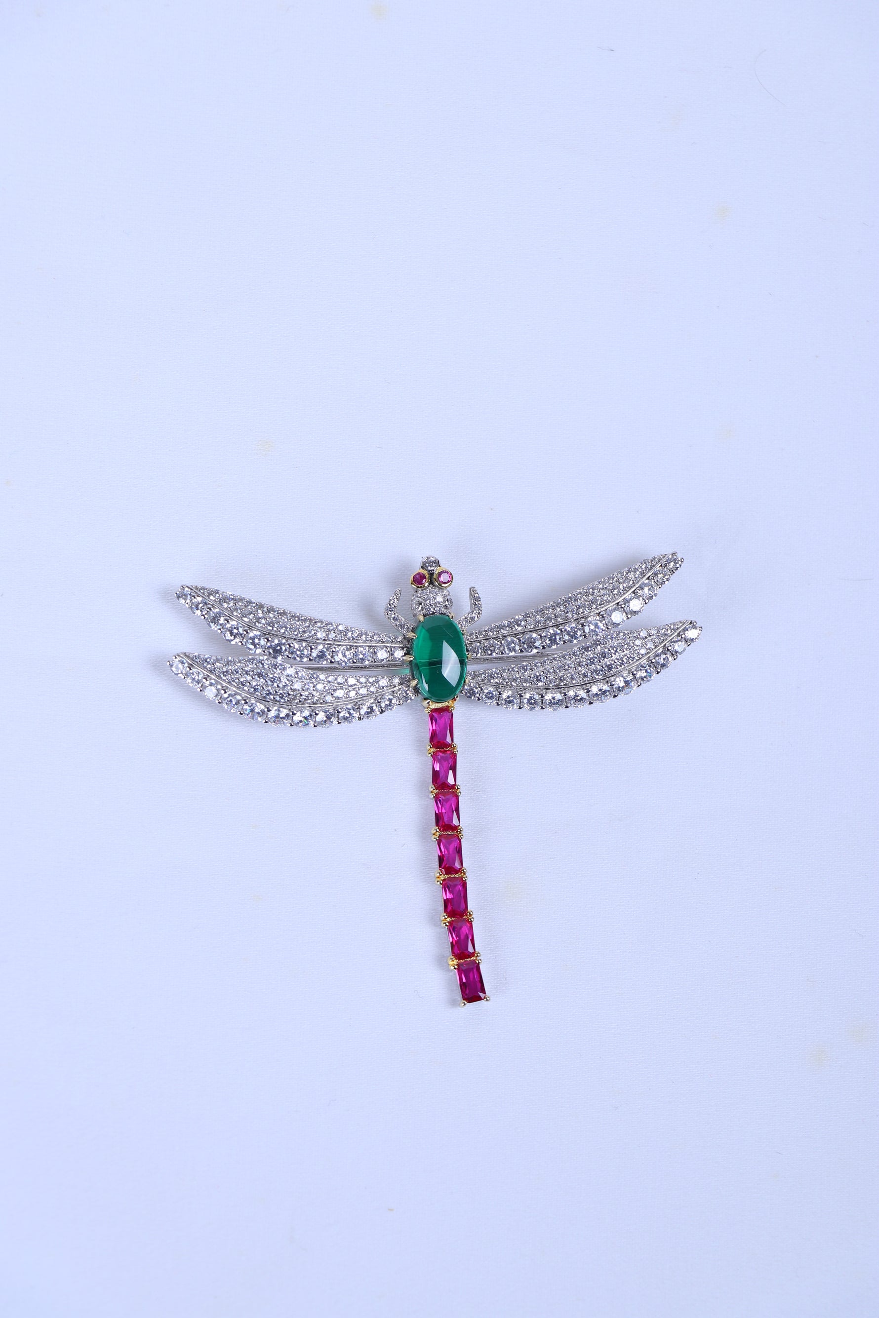 Silver wing brooch for men with green centre stone and pink hanging stone detail.