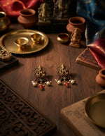 Traditional temple-style silver earrings featuring a Ganesha motif, pearls and red stone drops.