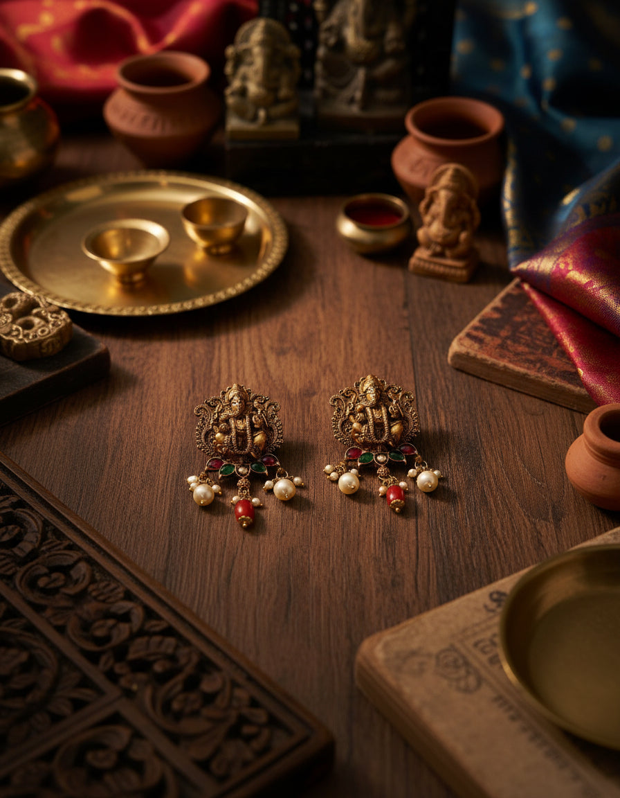 Traditional temple-style silver earrings featuring a Ganesha motif, pearls and red stone drops.