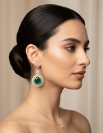 Woman wearing green stone silver earrings with a gold finish and delicate crystal detailing.