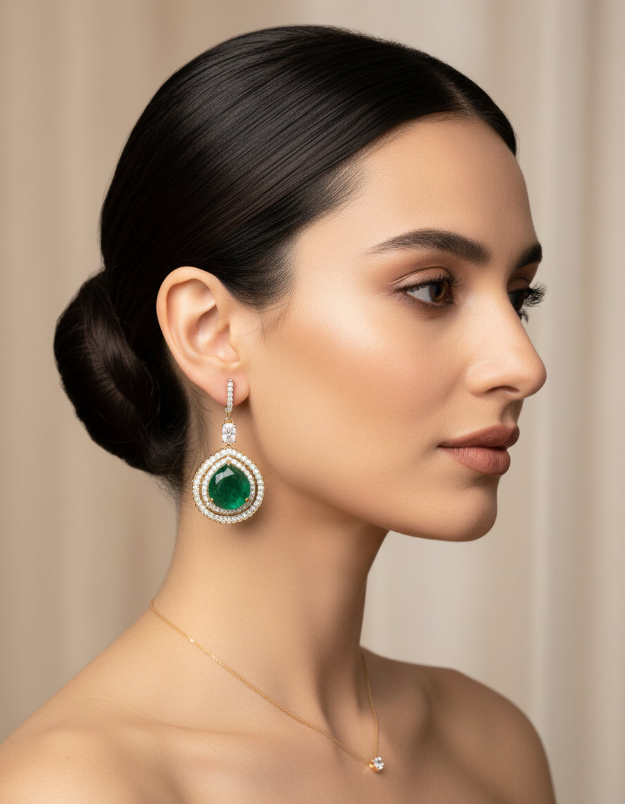 Woman wearing green stone silver earrings with a gold finish and delicate crystal detailing.