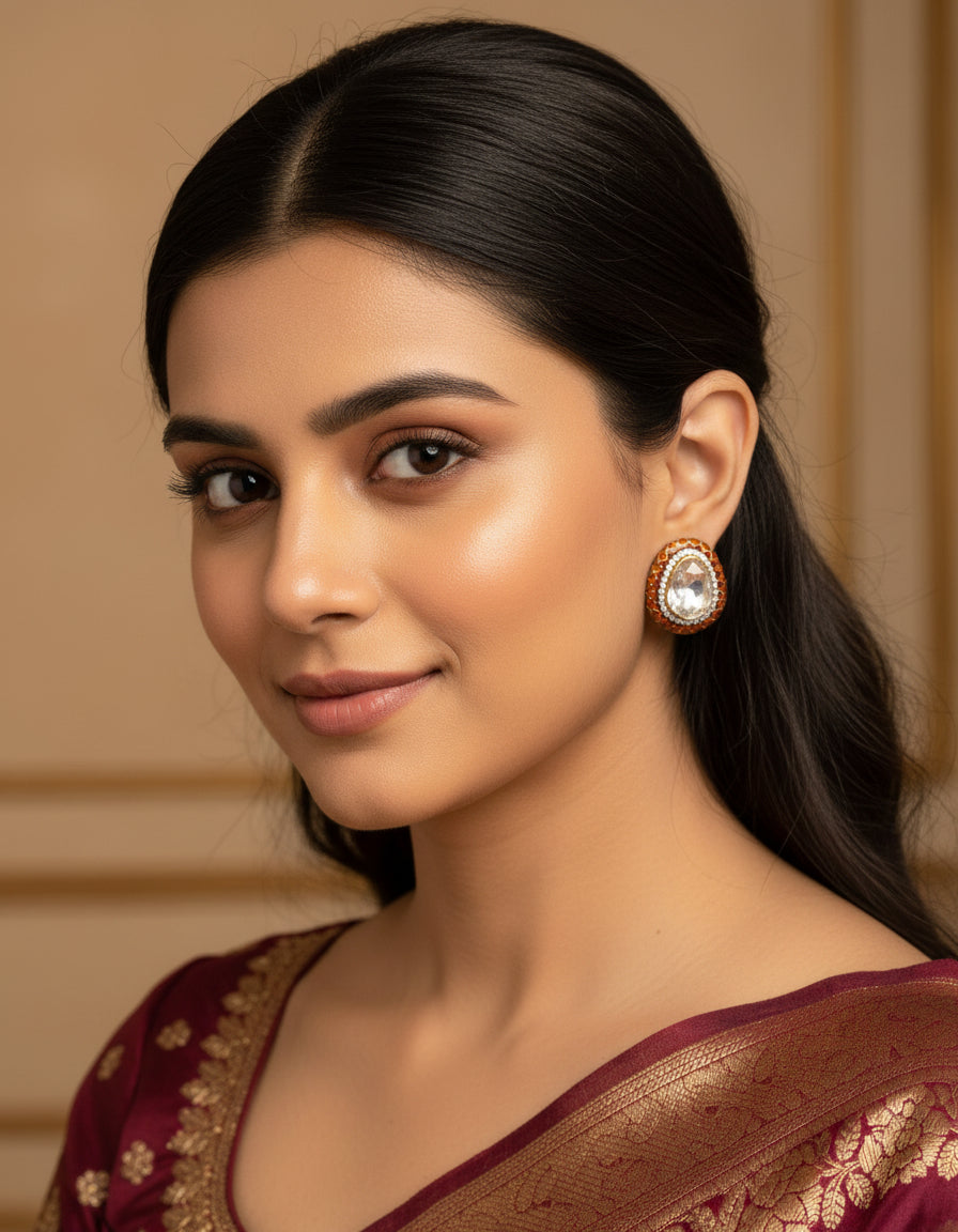 Woman wearing oval pure silver earrings with a white centre stone and orange enamel border.