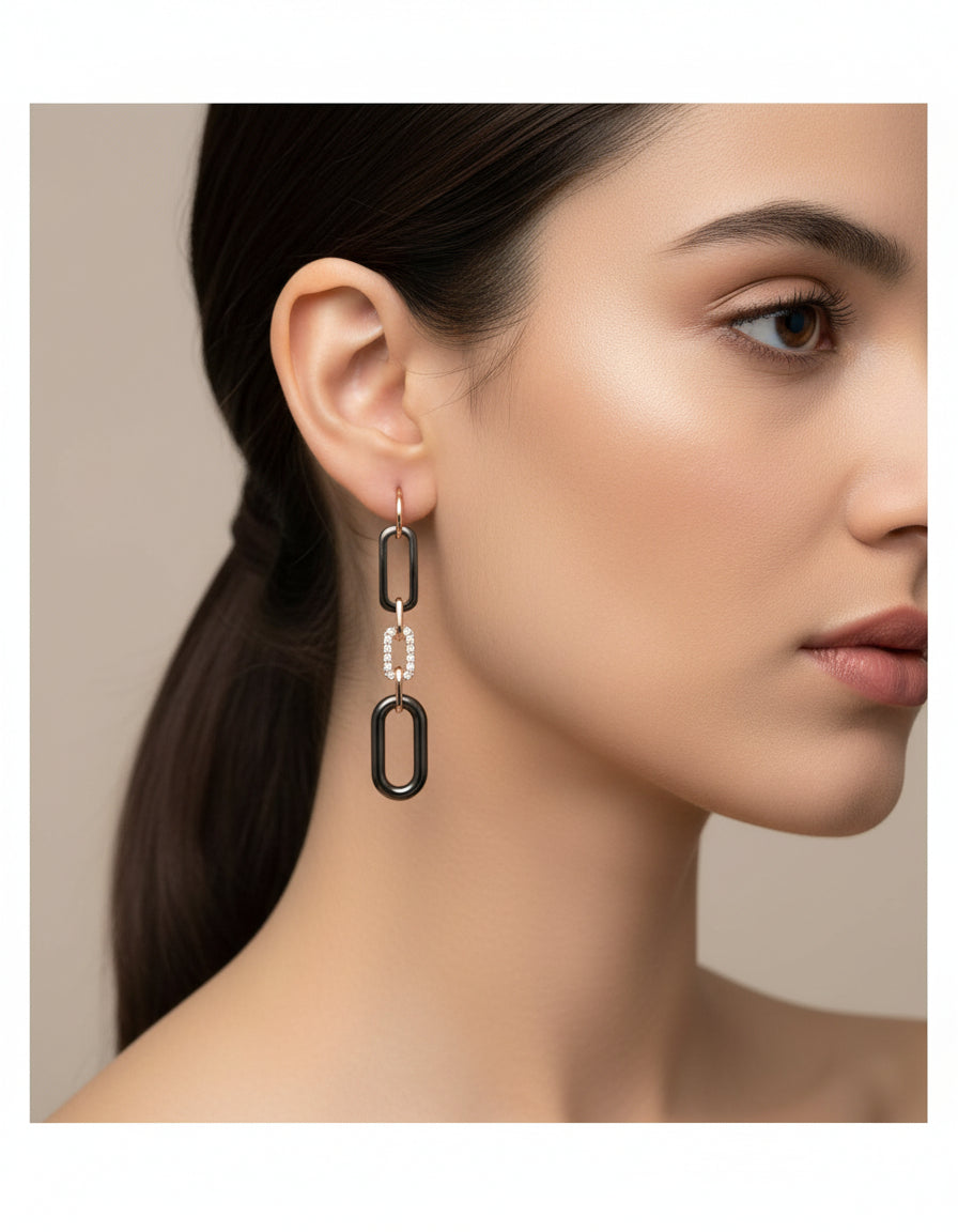 Woman wearing long silver chain earrings with black links, rose-gold finish and crystal accents.
