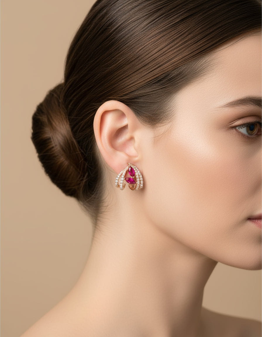 Woman wearing elegant silver stud earrings with pink stones and curved crystal embellishments.