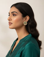 Woman wearing statement silver stud earrings with green floral accents and layered white stones.
